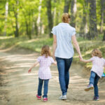 Mutter mit Zwillingen geht im Wald spazieren