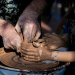 Adulto che guida un bambino nella lavorazione della ceramica