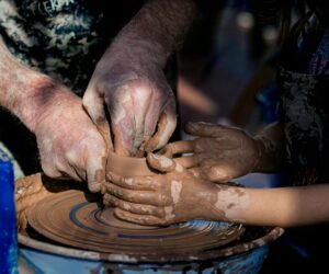 Adulto che guida un bambino nella lavorazione della ceramica