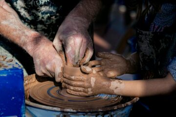 Adulto che guida un bambino nella lavorazione della ceramica