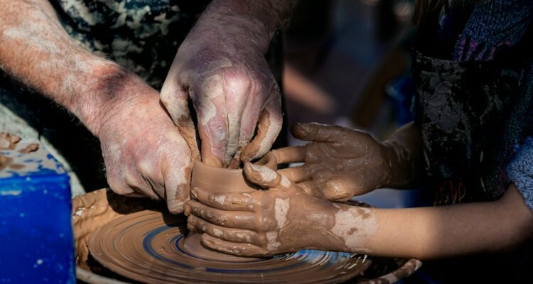 Adulto che guida un bambino nella lavorazione della ceramica